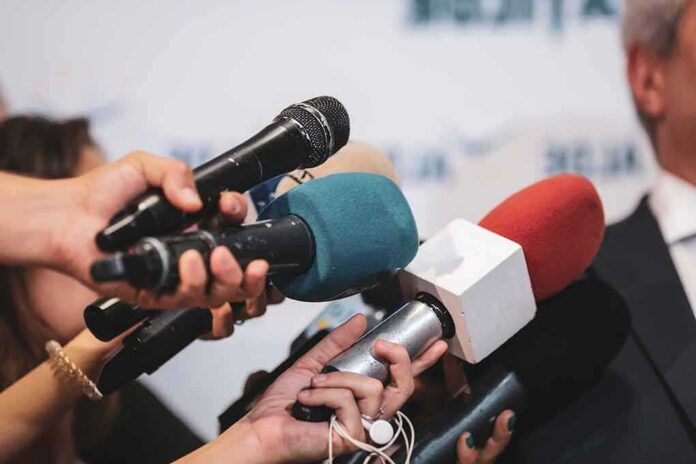 Cluster of microphones held toward a speaker at a press event