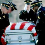 Honor guard carrying a flag-draped casket