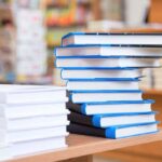 A stack of neatly arranged books on a wooden table in a bookstore
