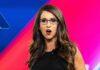 Woman with glasses speaking on stage with colorful backdrop