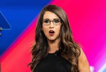 Woman with glasses speaking on stage with colorful backdrop