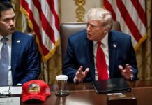 Trump Takes Wrecking Ball to JFK Memorial Building Man in suit with red tie speaks at meeting table