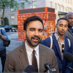 Zohran Mamdani speaking to reporters on a city sidewalk