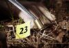 Forensic gloved hand collecting a bullet casing near evidence marker
