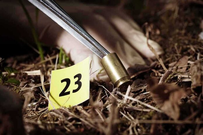 shutterstock_285615599 Forensic gloved hand collecting a bullet casing near evidence marker