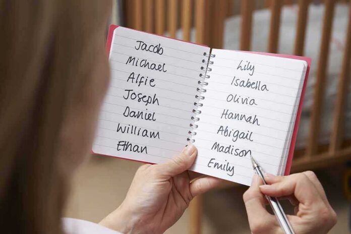 shutterstock_345850001 Hands holding a notebook with baby name lists near a crib