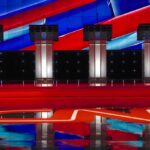 Debate stage with four empty podiums and bright red and blue backdrop