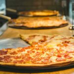 Popular Pizza Chain Raided in Meth Scandal Pepperoni pizza slices on metal trays