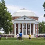Students playing on a lawn in front of a domed neoclassical building