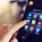 Finger tapping smartphone social media app icons.