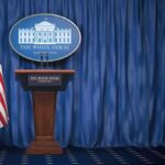 Trump’s New Press Sec Sparks Immediate Showdown White House press briefing podium with U.S. flag and blue curtain