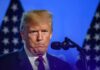 Trump Rages at Reporter – Bares His Teeth Donald Trump at a podium with U.S. flags in the background