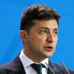Trump Taunt Ignites Wartime Election Bomb Volodymyr Zelensky speaking at a podium against a blue backdrop