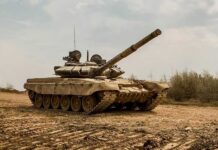 Main battle tank on muddy terrain with elevated gun barrel