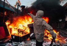 France Descends into CHOAS – Riots Erupt into War Hooded person throws object near street fire