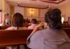 Woke Senate Candidate Calls for Repentance Over White Privilege people seated in church pews facing a cross