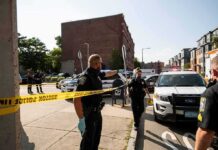 WILD Footage of Assassin’s Arrest Has Been Unsealed Police officers secure an urban street with yellow tape near patrol cars