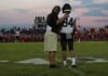 football coach with arm around player number 84 on sideline