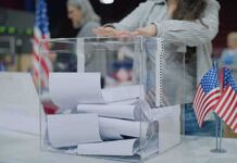 Person casting a ballot into a clear box at a polling station