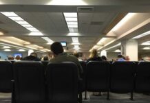 People seated in a waiting room with rows of chairs