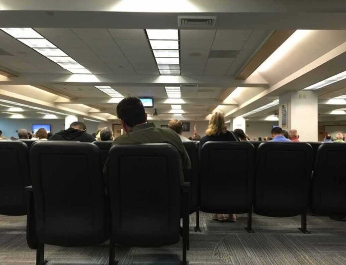 People seated in a waiting room with rows of chairs