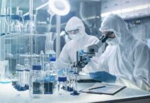 Hundreds of Russians in Plague Lockdown Panic Scientists in protective suits using a microscope in a laboratory