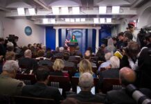Trump Judge Hands Media Indefinite White House Access Press secretary at podium addressing reporters in briefing room