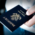 A person holding a United States passport with a dark background